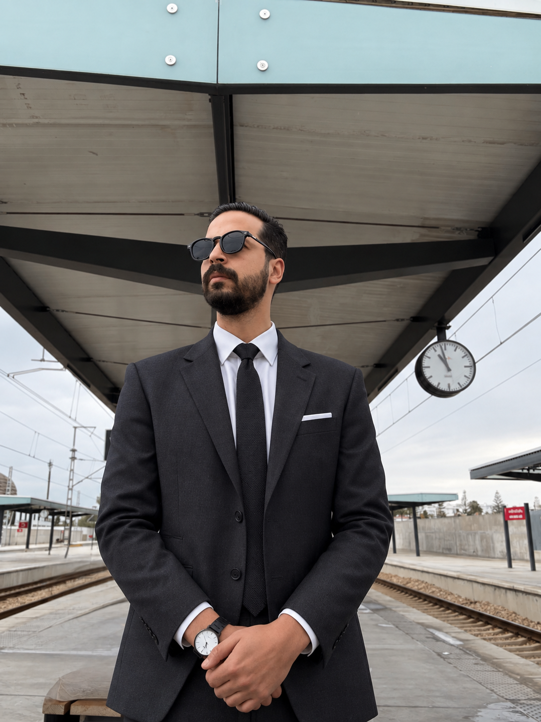 Saad Boukhrouf wearing a dark suit and sunglasses at a railway station